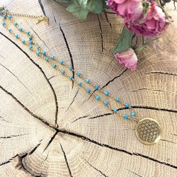 Collier avec de petites perles bleus orné d'un pendentif graine de vie