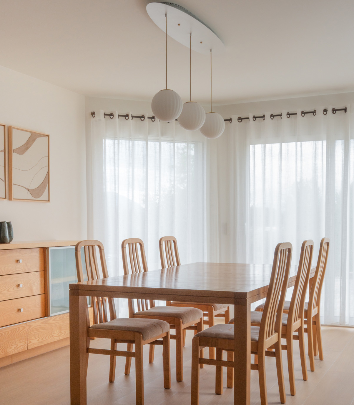 Support de fixation sur mesure Il-umine intégrant trois suspensions Nordic Nest au-dessus d'une table à manger.